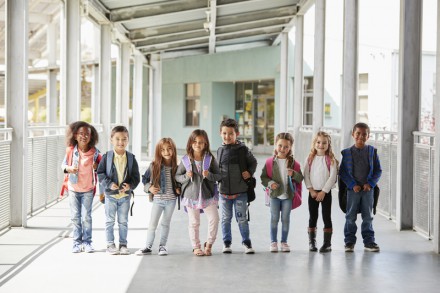 Elementary school class standing in corridor with their bags