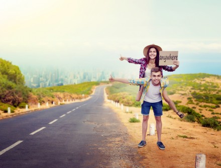 Hitchhiking couple holds blank cardboard, happy hitchhikers travels anywhere. Hitchhike adventure of young man and woman