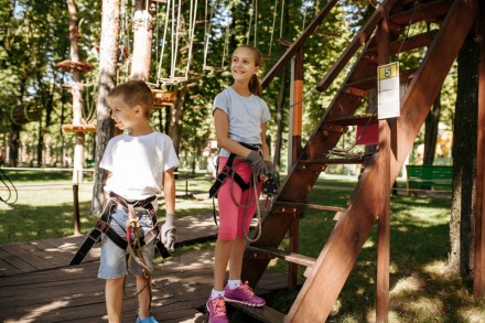 Little kids in equipment, rope park, playground. Children climbing on suspension bridge, extreme sport adventure on vacations, danger entertainment outdoors