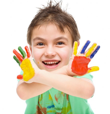 Portrait of a cute cheerful boy showing her hands painted in bright colors, isolated over white
