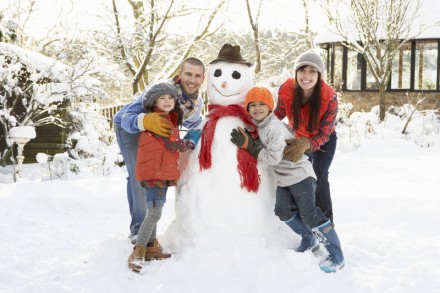 Family Building Snowman In Garden