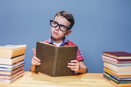 Young pupil in glasses getting knowledge from a textbook. Education concept