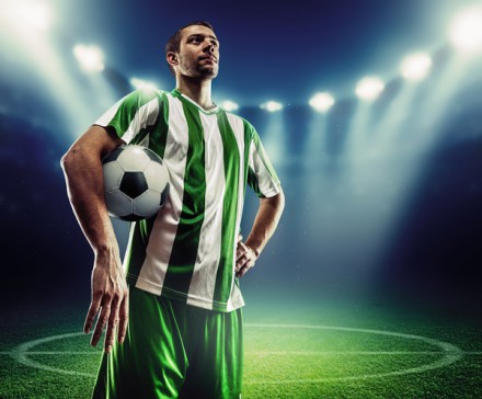 Football player holding a ball on the football ground at night