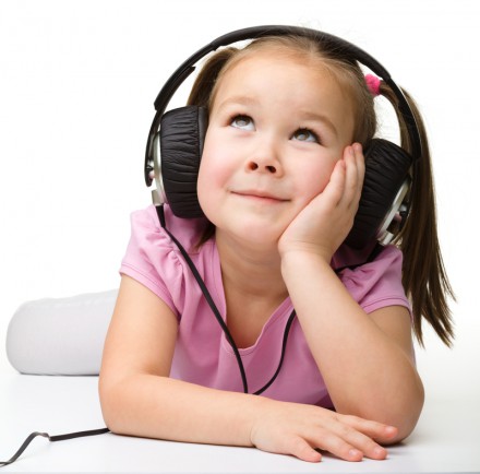 Cute little girl enjoying music using headphones, isolated over white