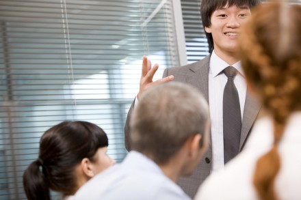 Photo of several employees during presentation with focus on their leader