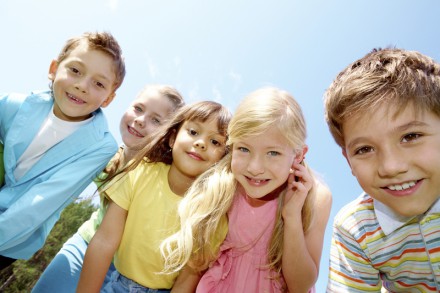Portrait of smiling children looking at camera on background of blue sky